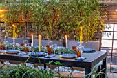 TANYA SOUTHWORTH GARDEN, LONDON, DESIGNER ANOUSHKA FEILER: SMALL GARDEN - TABLE, BENCHES, CANDLES, MIRRORS, CONTAINERS WITH BLACK BAMBOO, LIGHTING, EVENING, NIGHT, FORMAL