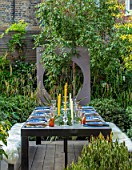 TANYA SOUTHWORTH GARDEN, LONDON, DESIGNER ANOUSHKA FEILER: TABLE, BENCHES, CANDLES, DOG, PET, RENDERED WALL WITH CIRCULAR OPENING, SMALL, FORMAL, TOWN, URBAN