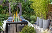 TANYA SOUTHWORTH GARDEN, LONDON, DESIGNER ANOUSHKA FEILER: TABLE, BENCHES, CANDLES, RENDERED WALL WITH CIRCULAR OPENING, CONTAINERS WITH BAMBOO, SMALL, FORMAL, TOWN, URBAN