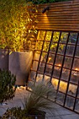 TANYA SOUTHWORTH GARDEN, LONDON, DESIGNER ANOUSHKA FEILER: ANTIQUE MIRROR, CONTAINERS WITH BAMBOO, SMALL, FORMAL, TOWN, URBAN, NIGHT, LIGHTS