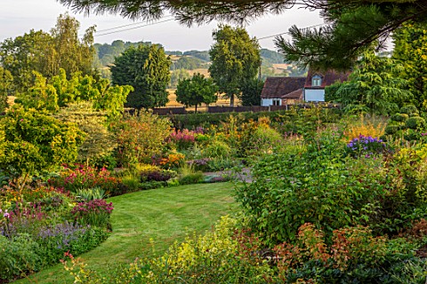 MEADOW_FARM_GARDEN_AND_NURSERY_WORCESTERSHIRE_EVENING_LIGHT_ON_LAWN_AND_BORDERS_ENGLISH_COUNTRY_GARD