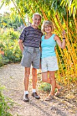 MEADOW FARM GARDEN AND NURSERY, WORCESTERSHIRE: GARDEN OWNERS ROB AND DIANE COLE BESIDE PHYLLOSTACHYS VIVAX AUREOCAULIS