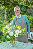 CLAUS DALBY GARDEN, DENMARK: CLAUS DALBY ARRANGING A BOUQUET OF WHITE FLOWERS FROM THE GARDEN