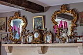 PYTTS HOUSE, OXFORDSHIRE: THE DINING ROOM. MIRRORS, PICTURES, CANDELABRAS AND CLOCKS ON MANTELPIECE ABOVE THE FIREPLACE