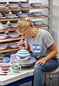 ALHAM FARM, SOMERSET: CORNISHWARE: THE POTTERY - VICKY APPLYING ICONIC BLUE STRIPE BY HAND TO FIRED BOWLS