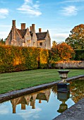 RADCOT HOUSE, OXFORDSHIRE: THE HOUSE SEEN FROM THE LONG POND. BEECH HEDGES, HEDGING, POOL, CANAL, AUTUMN, REFLECTIONS, REFLECTED