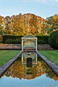 RADCOT HOUSE, OXFORDSHIRE: THE LONG POND. BEECH HEDGES, HEDGING, POOL, CANAL, GAZEBO, SEAT, SEATING, AUTUMN, REFLECTIONS, REFLECTED
