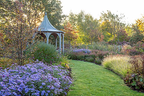 RADCOT_HOUSE_OXFORDSHIRE_GRASS_PATH_TO_PAVILION_WITH_SESLERIA_AUTUMNALIS_AND_ASTER_X_FRIKARTII_MONCH