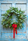 FLOWERS FROM THE FARM, MARBURY HALL, DESIGNER SOFIE PATON-SMITH: NATURAL WREATH WITH RED RIBBON. BLUE DOOR, YEW, EUCALYPTUS