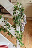 THE CONIFERS, OXFORDSHIRE: CHRISTMAS - KITCHEN DINING ROOM - STAIRCASE WITH IVY AND WHITE SPRAYED PINE CONES, DECORATIONS, NATURAL