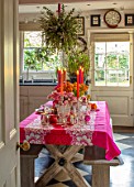 BUTTER WAKEFIELD HOUSE, LONDON: CHRISTMAS - KITCHEN - TABLE, PINK TABLECLOTH, CANDLES, TULIPS, ANEMONES, RANUNCULUS