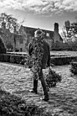 WARDINGTON MANOR, OXFORDSHIRE: BLACK AND WHITE PHOTO OF FLORIST SHANE CONNOLLY CARRYING IVY CUT FROM THE GARDEN