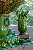 MERRYWOOD, JACKY HOBBS HOUSE, LONDON: DINING AREA, GREEN GLAZED CONTAINER WITH WHITE TULIPS, CHRISTMAS TREE, GREEN GLASS TEALIGHTS, VINTAGE BOOKS