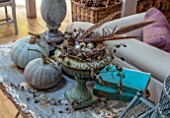 MERRYWOOD, JACKY HOBBS HOUSE, LONDON: DINING ROOM - CHRISTMAS DECORATION. GREY PUMPKINS, METAL VERDIGRIS URN, CONTAINER WITH BIRDS NEST, QUAILS EGGS, PHEASANT FEATHERS