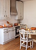 MERRYWOOD, JACKY HOBBS HOUSE, LONDON: WHITE KITCHEN, CHRISTMAS: ORANGE PUMPKINS, TABLE AND CHAIRS