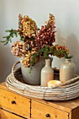 MERRYWOOD, JACKY HOBBS HOUSE, LONDON: DISPLAY OF NATURAL DRIED HYDRANGEAS IN VINTAGE FRENCH COMPOTE JAR, STONE WARE BOTTLES, CANDLE, WICKER TRAY