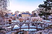 THE OLD RECTORY, QUINTON, NORTHAMPTONSHIRE: DESIGNER ANOUSHKA FEILER: BRIDGE, LAKE TO RECTORY WITH GRASSES AND WOODEN PONTOON, FROST, WINTER, FROSTY GARDEN, ENGLISH, COUNTRY
