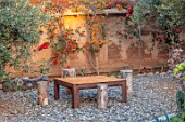 TAROUDANT, MOROCCO: DESIGNERS ARNAUD MAURIERES AND ERIC OSSART: WOODEN TABLE AND CHAIRS, MUD WALL, BOUGAINVILLEA, CLIMBERS, ARID, DRY, GRAVEL