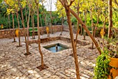 TAROUDANT, MOROCCO: DESIGNERS ARNAUD MAURIERES AND ERIC OSSART: RECTANGULAR GARDEN, WATER, POND, POOL, FOUNTAIN, PATIO, PAVING, GREEN BENCHES, SEATS, ACACIA TREES, SHADE, SHADY