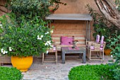 TAROUDANT, MOROCCO: DESIGNERS ARNAUD MAURIERES AND ERIC OSSART: COVERED SEATING AREA WITH CHAIRS, TABLE AND SWING SEAT. AWNINGS, CANOPY, CANOPIES, YELLOW CONTAINER WITH OLEANDER