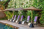 TAROUDANT, MOROCCO: DESIGNERS ARNAUD MAURIERES AND ERIC OSSART: SWIMMING POOL, DECKCHAIRS, DECK CHAIRS, PURPLE TOWELLS, SHADES, SHADY, BOUGAINVILLEA, HEDGES, HEDGING