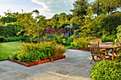 DESIGNER JAMES SCOTT, THE GARDEN COMPANY: STONE TERRACE, PATIOS, PAVED, CORTEN STEEL EDGED BEDS, TABLE AND CHAIRS, AMELANCHIER X GRANDIFLORA ROBIN HILL