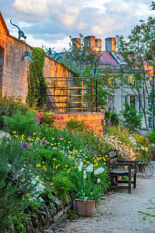 PAINSWICK_ROCOCO_GARDEN_GLOUCESTERSHIRE_ART_UNBOUND_WALL_AND_BORDER_AT_TOP_OF_GARDEN_WITH_WOODEN_BEN
