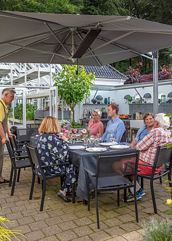 CLAUS_DALBY_GARDEN_DENMARK_CLAUS_AND_FRIENDS_EATING_AT_A_TABLE_ON_PATIO