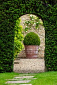 WINSON MANOR, GLOUCESTERSHIRE: LAWN, PATH, YEW HEDGES, HEDGING, GRAVEL, COURTYARD,TERRACOTTA CONTAINER, BOX BALLS, CLIPPED, TOPIARY, SUMMER, ARCH, ARCHWAY