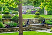 WINSON MANOR, GLOUCESTERSHIRE: LAWN, RAISED BED, YEW TOPIARY ON LAWN, CATALPA, STATUES, WALLS, SUMMER, BORDERS, STEPS
