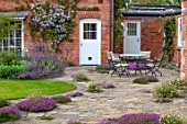 MORTON HALL, WORCESTERSHIRE: PATIO, TABLE, CHAIRS, TERRACE, PAVING, ERIGERON ANNUUS, THYMES, THYMUS SERPHYLLUM RUSSETINGS, CLEMATIS PRINCE CHARLES