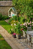 ADAMS POOL, GLOUCESTERSHIRE: VIEW FROM BEDROOM WINDOW ALONG PATH, LAWN, SWEET PEAS IN CONTAINER, TABLE AND CHAIRS, COVERED SEAT, BENCH