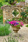 ADAMS POOL, GLOUCESTERSHIRE: HEMEROCALLIS, GRAVEL COURTYARD, STONE CONTAINER, FOLLY WALL WITH QUATREFOIL RECYCLED CHURCH WINDOW
