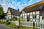 THATCH COTTAGE, WORCESTERSHIRE: THATCHED, FRONT, WHITE, PICKET FENCE, FENCING, BLACK AND WHITE COTTAGE, HOLLYHOCKS, GARDEN, ENGLISH, COTTAGES