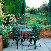 FORMAL GARDEN: FLAGSTONE PATIO WITH TABLE & CHAIRS BESIDE BED OF ROSES & VALERIAN. DESIGNER: JILL BILLINGTON