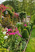 ADAMS POOL, GLOUCESTERSHIRE: BORDER BY LAWN, BOX TOPIARY, PHLOX, ARCHWAY, CLEMATIS MADAME JULIA CORREVON