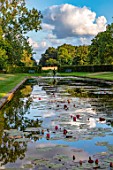PRIVATE GARDEN, GLOUCESTERSHIRE - DESIGNER ANGEL COLLINS: VIEW ACROSS THE WATERLILIES IN LAKE TO FOUNTAIN, AUGUST, EVENING