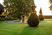 MITTON MANOR, STAFFORDSHIRE: FOUNTAIN AND CLIPPED YEW TOPIARY IN THE FRONT GARDEN. FOUNTAIN, POOL, FORMAL, LAWN, SUNRISE, COUNTRY, GARDEN, ENGLISH, LAWN, WATER