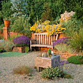 GRAVEL GARDEN:FRAGRANT BENCH IN BRICK ALCOVE SURROUNDED BY LAVENDER  HELICHRYSUM & AGAVES IN POTS. THE OLD VICARAGE  NORFOLK.