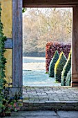BRYANS GROUND, HEREFORDSHIRE: THE DOVECOTE GARDEN, BUILDING, DOORWAY, CLIPPED YEW TOPIARY OBELISKS, VIEW OUT TO COUNTRYSIDE, ENGLISH, GARDEN, BEECH, HEDGES, HEDGING, FROSTY