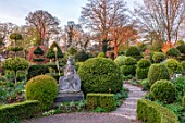 THE LASKETT GARDENS, HEREFORDSHIRE. DESIGNER ROY STRONG - THE SERPENTINE WALK - STATUE OF BRITANNIA, PATHS, CLIPPED, TOPIARY, BOX, HOLLY, ILEX, BUXUS, ACER GRISEUM, SPRING, APRIL