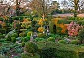 THE LASKETT GARDENS, HEREFORDSHIRE. DESIGNER ROY STRONG - THE SERPENTINE WALK - MAGNOLIA, PATHS, CLIPPED, TOPIARY, BOX, HOLLY, ILEX, BUXUS, SPRING, APRIL, YEW HEDGING