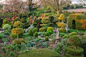 THE LASKETT GARDENS, HEREFORDSHIRE. DESIGNER ROY STRONG - THE SERPENTINE WALK - MAGNOLIA, ACER GRISEUM, PATHS, CLIPPED, TOPIARY, BOX, HOLLY, ILEX, BUXUS, SPRING, APRIL, YEW HEDGING