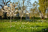MORTON HALL GARDENS, WORCESTERSHIRE: THE MEADOW, PARK, SPRING, APRIL, MONOPTEROS, FOLLY, FOLLIES, DAFFODILS, NARCISSUS, CHERRIES, PRUNUS FRAGRANT CLOUD