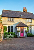 LITTLE ORCHARDS, SURREY, DESIGNER NIC HOWARD: THE FRONT OF THE HOUSE, DRIVE, PINK DOOR, METAL TABLE AND CHAIRS, SILVER METAL CONTAINERS, SPRING, APRIL, ROSEMARY, MORNING LIGHT