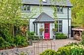 LITTLE ORCHARDS, SURREY, DESIGNER NIC HOWARD: THE FRONT OF THE HOUSE, DRIVE, PINK DOOR, METAL TABLE AND CHAIRS, SILVER METAL CONTAINERS, SPRING, APRIL, ROSEMARY