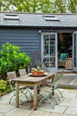 LITTLE ORCHARDS, SURREY, DESIGNER NIC HOWARD: COURTYARD, PATIO, WOODEN TABLE, CHAIRS, OFFICE, SHED, OUT BUILDING, HOME, PAVING, SPRING, APRIL