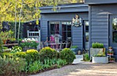 LITTLE ORCHARDS, SURREY, DESIGNER NIC HOWARD: DRIVE, HOME OFFICE, CLIPPED BOX HEDGES, HEDGING, TABLE, CHAIRS, METAL CONTAINER WITH TULIPS, SPRING, APRIL