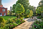 MORTON HALL GARDENS, WORCESTERSHIRE: TULIPS AND FOUNTAIN IN THE SOUTH GARDEN, LAWN, APRIL, SPRING, PATHS, MORNING LIGHT