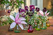 DESIGNER ANGELA COLLINS: RED AND GREEN GLASS JARS, CONTAINERS ON TABLE WITH MAGNOLIA AND TULIPS, FLOWER ARRANGEMENT, PURPLE, RED, PINK, FLOWERS, BLOOMS, APRIL, SPRING